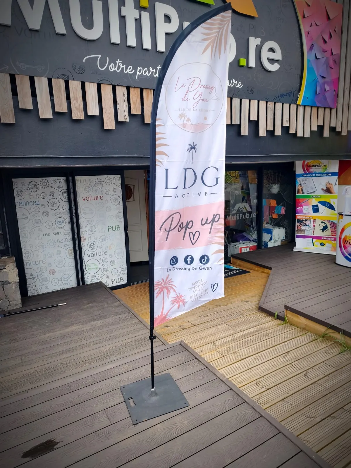 Drapeau personnalisé « Le Dressing de Gwen » sur son socle, devant la boutique MultiPub au Tampon