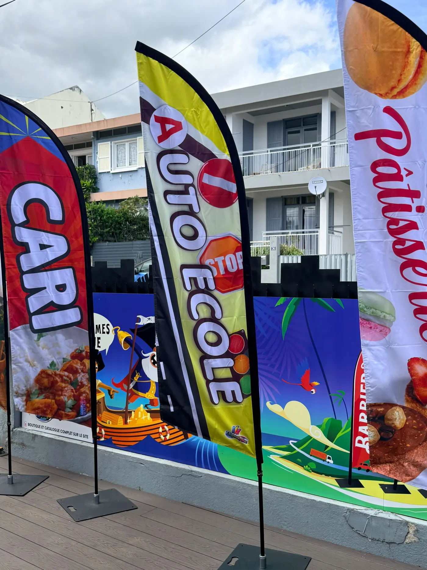 Trois drapeaux publicitaires alignés devant nos locaux